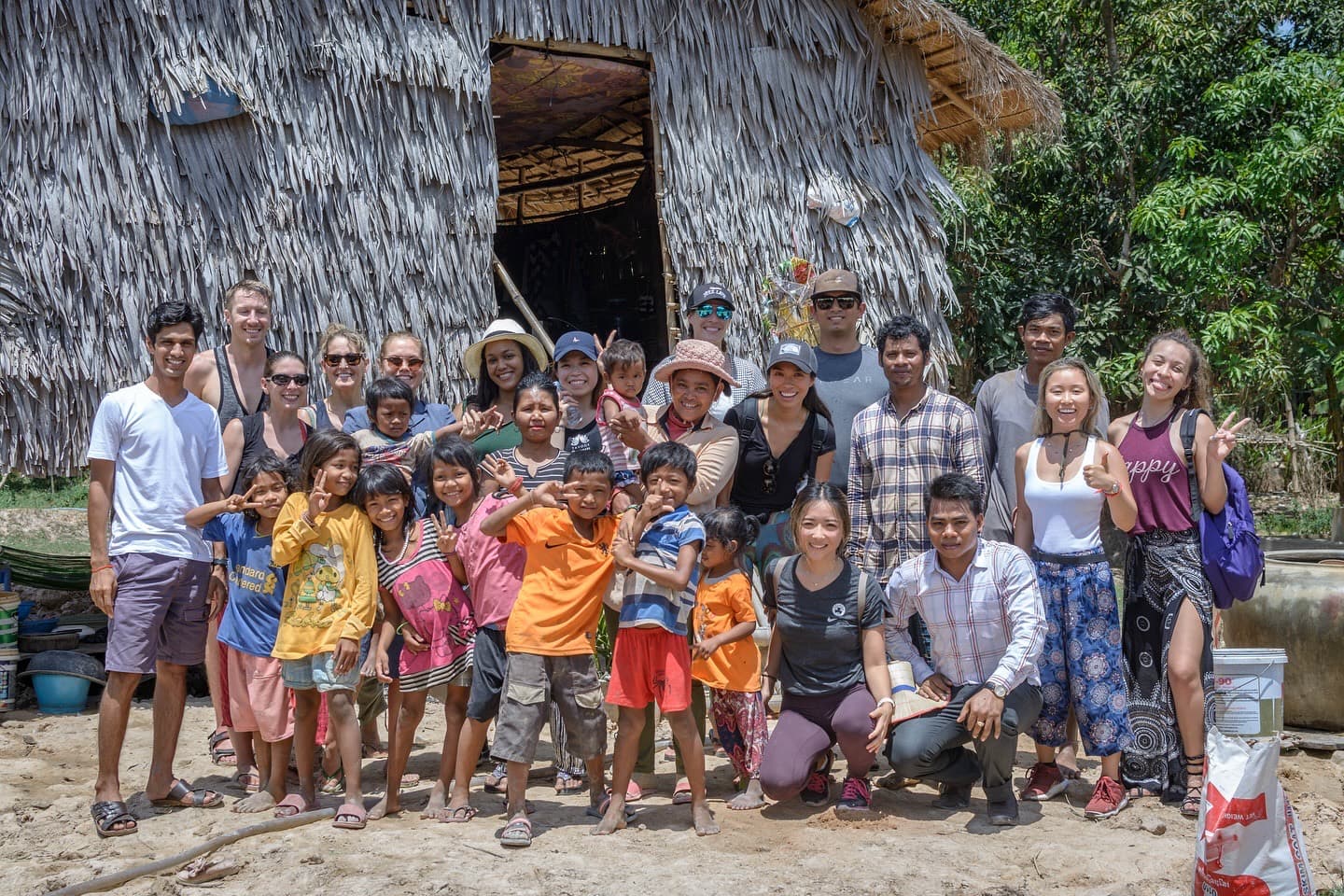 Students and a village family gathered outside their home
