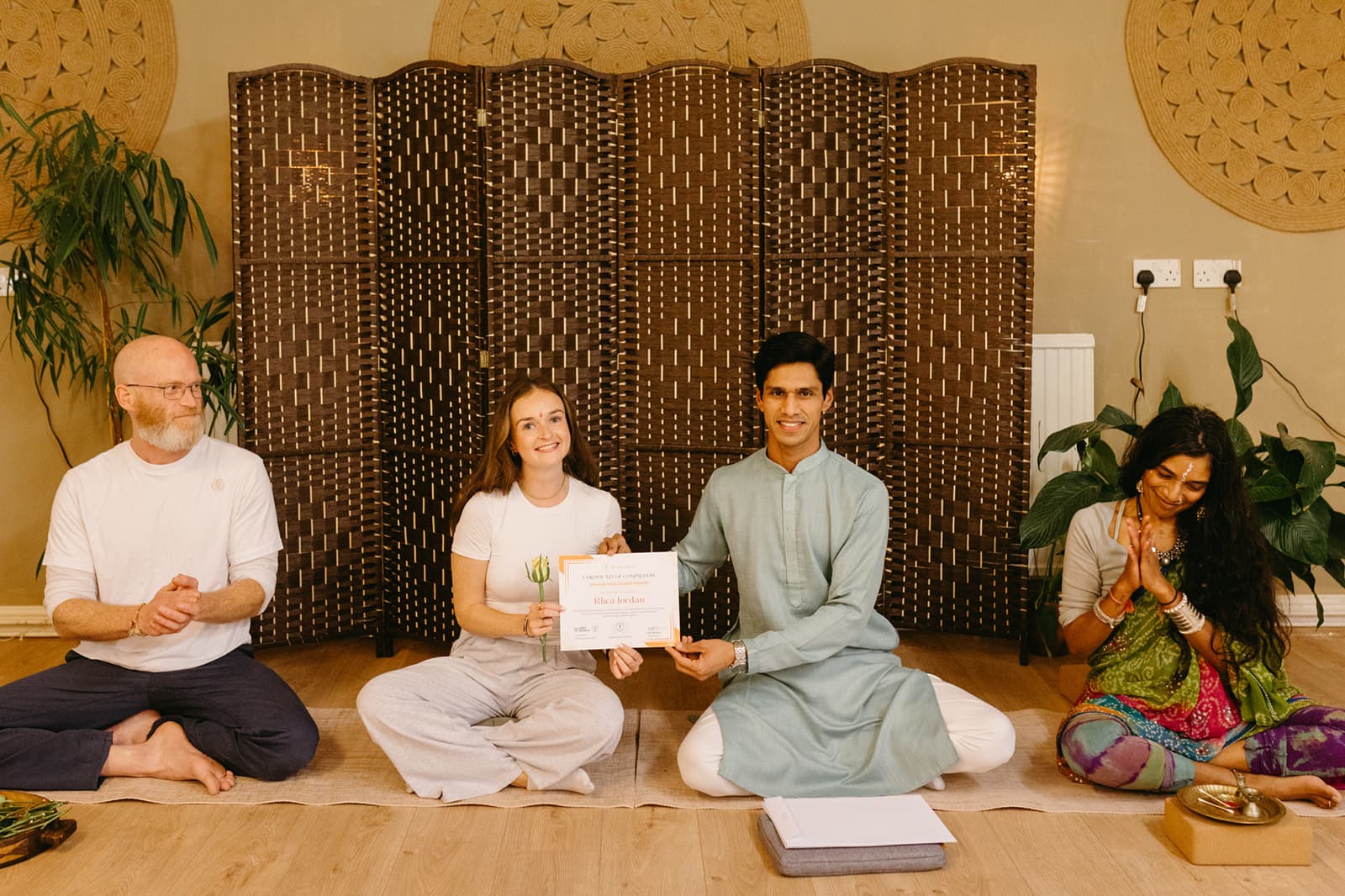 A graduate smiles with her certificate between two teachers