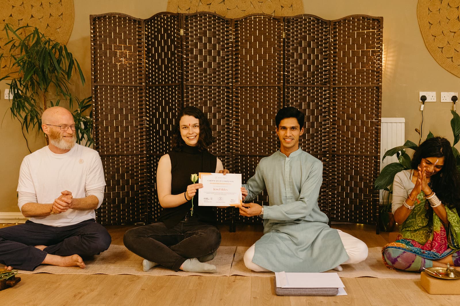 A graduate holds her certificate and a flower beside Yogi Madhav
