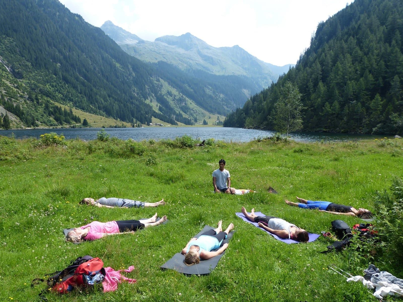 Guests lying in relaxation on an alpine meadow beside a lake
