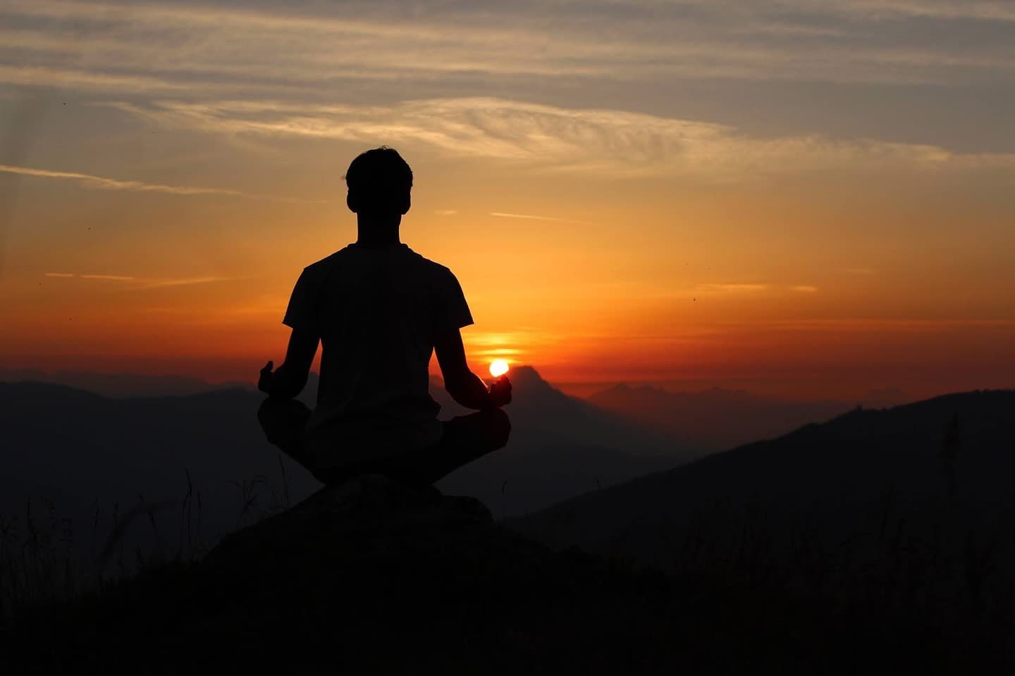 Silhouette of Yogi Madhav meditating on a mountain at sunrise