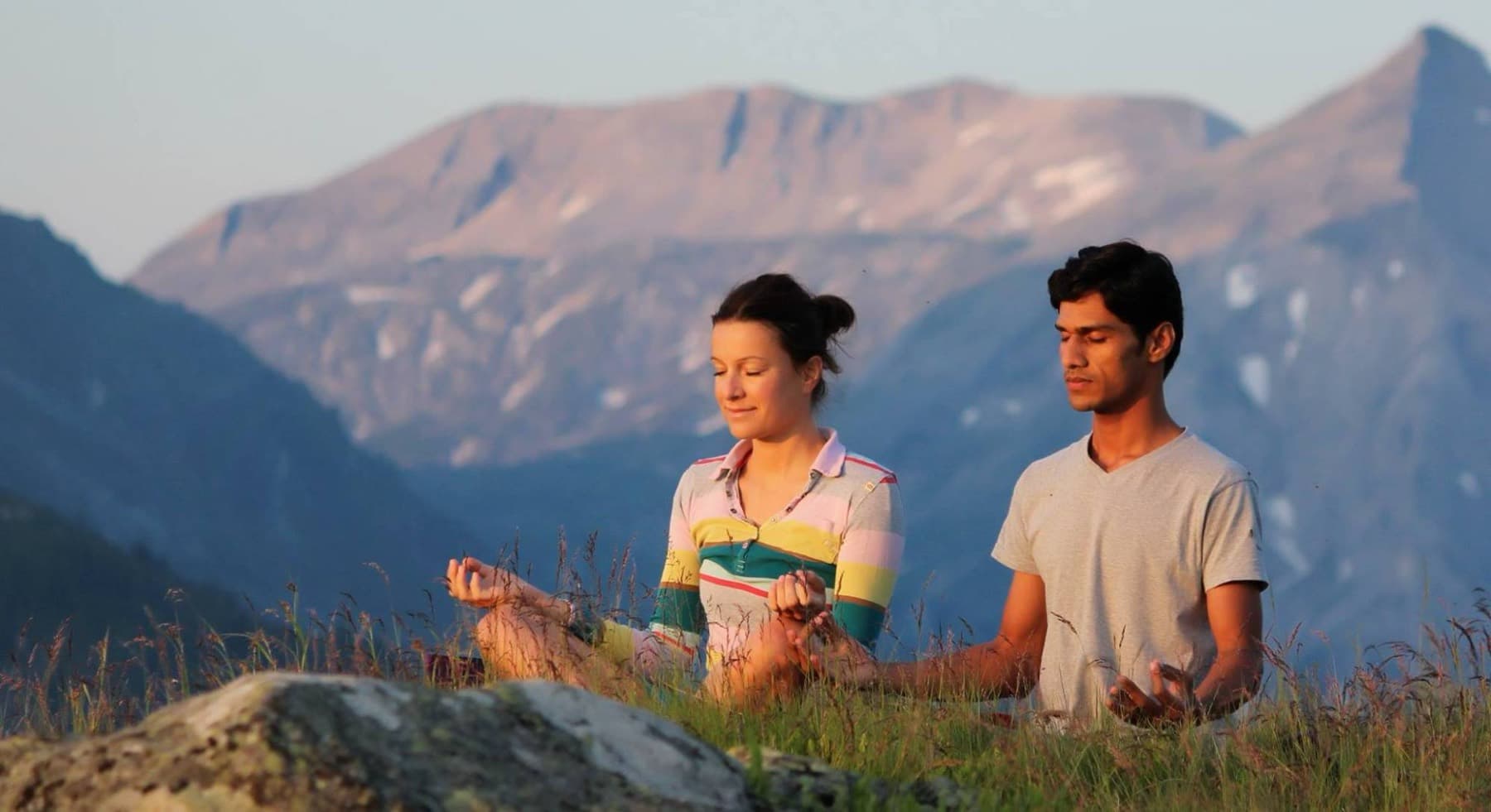 Yogi Madhav meditating with a student on an alpine meadow at sunrise