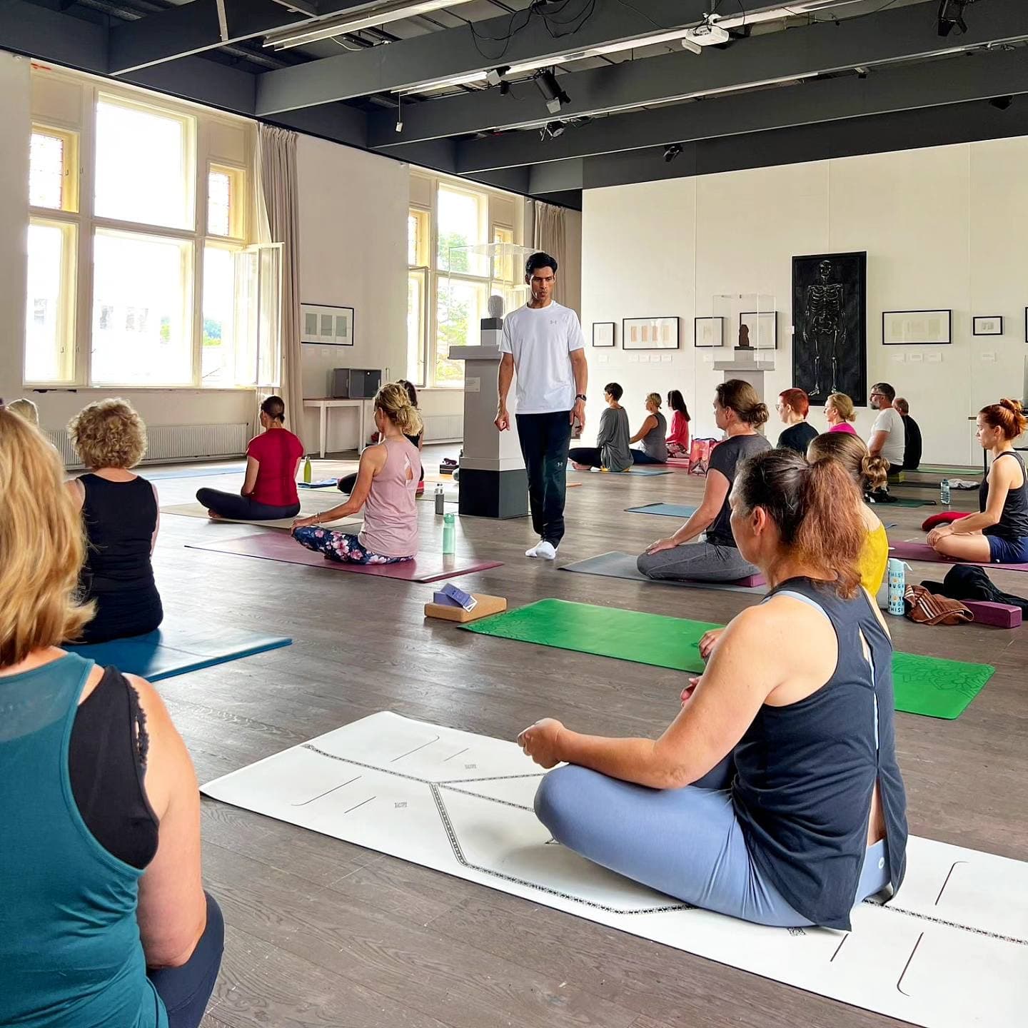 Yogi Madhav walking between seated students at a workshop in Austria