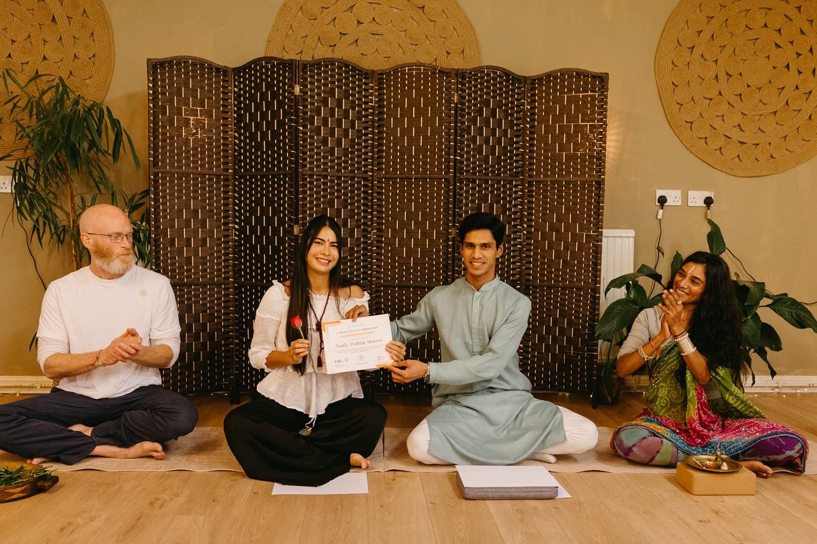 Yogi Madhav presenting a teacher training certificate to a graduate, teachers applauding