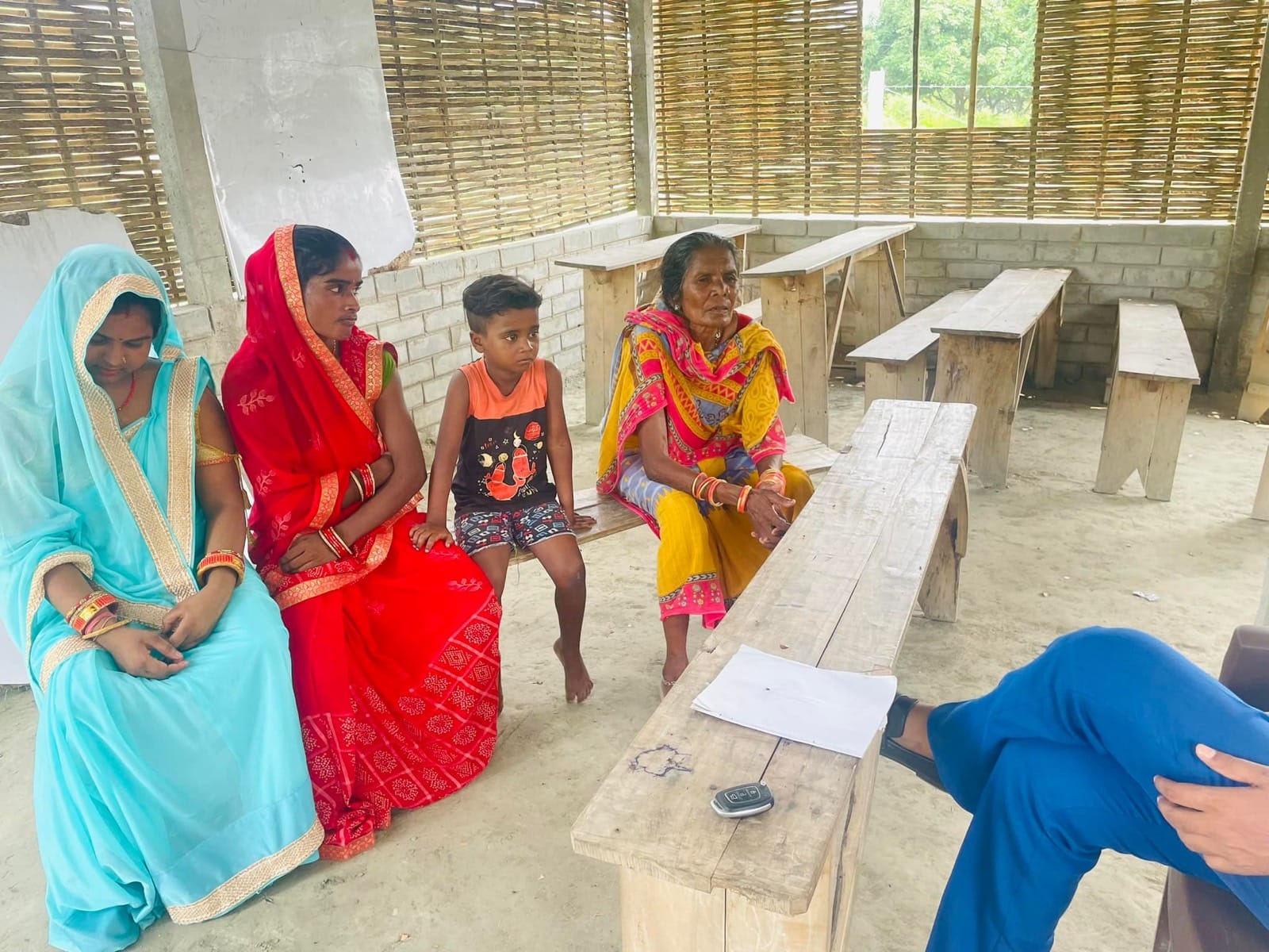 Women in colourful saris seated together at a workshop in a village school room