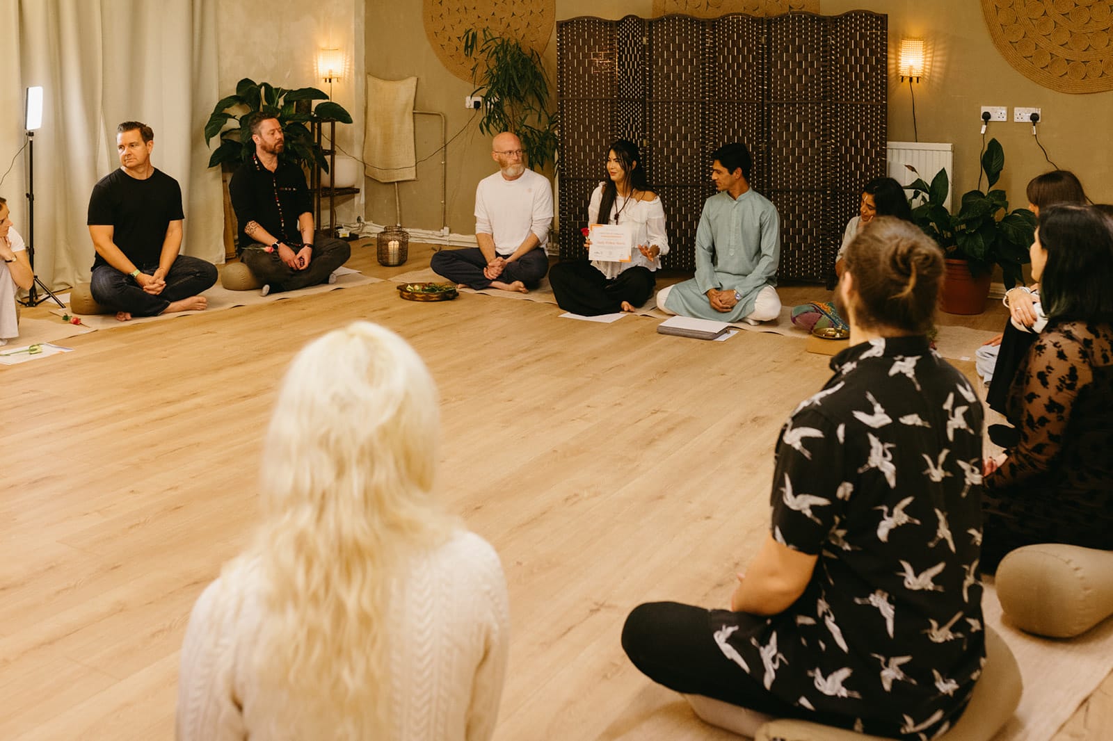 The training group seated in a wide circle on the studio floor