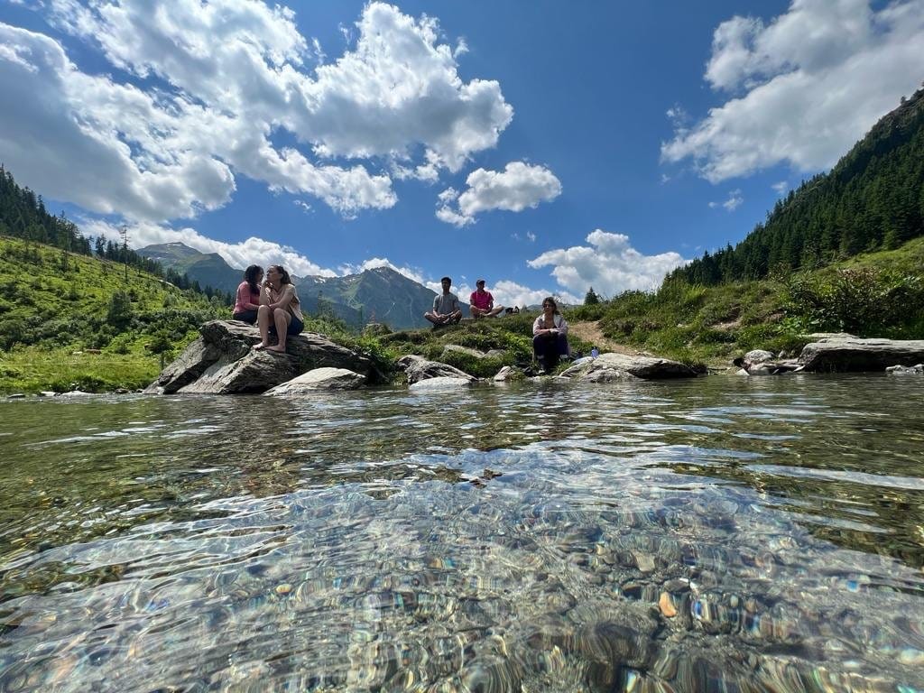 Guests resting on rocks beside a clear alpine stream