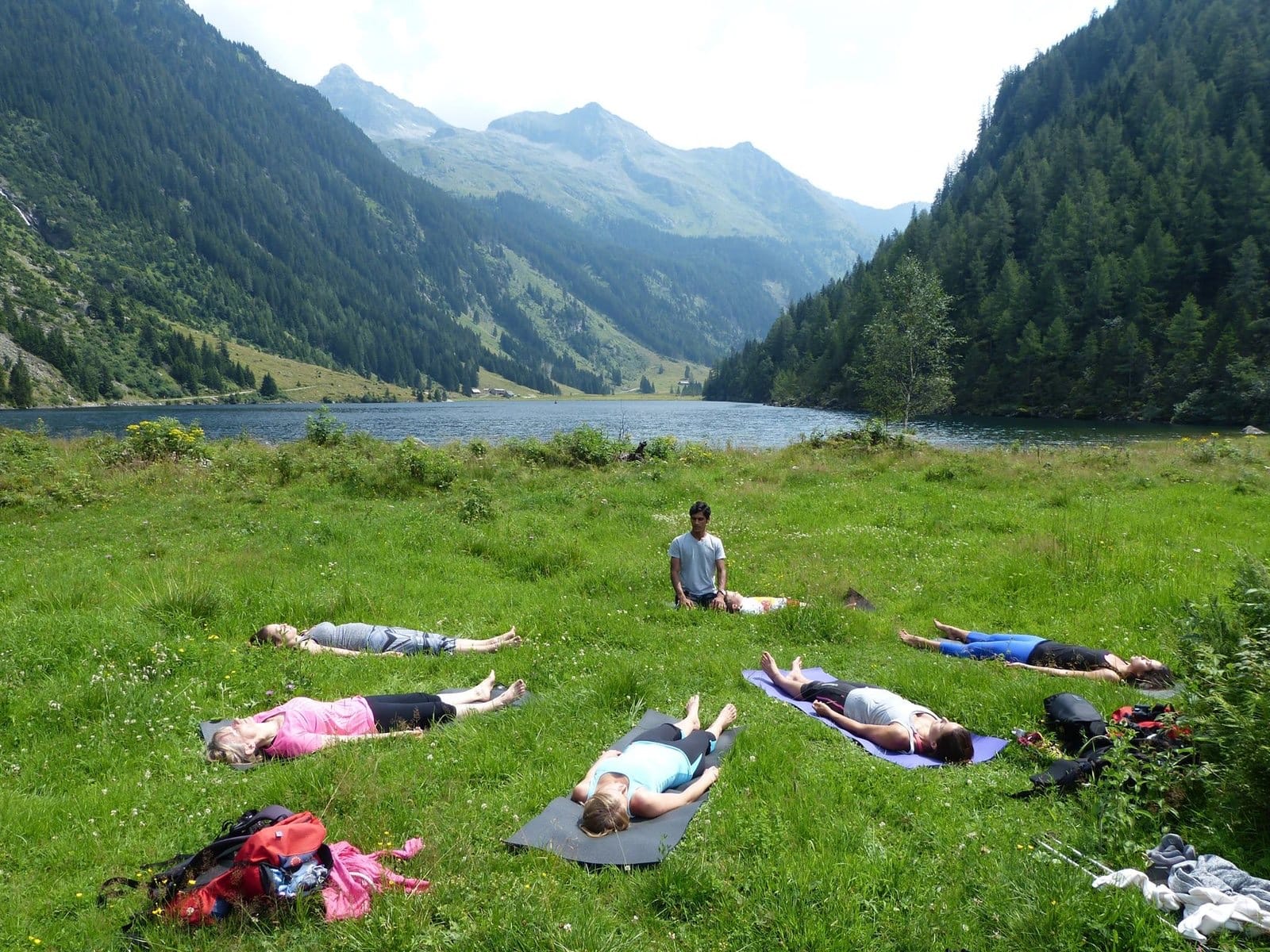 Guests lying in relaxation on an alpine meadow beside a lake