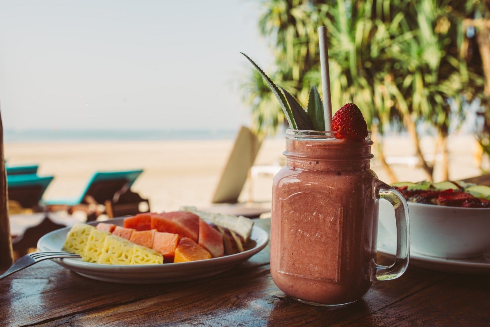Fresh fruit and a smoothie on a table by the beach