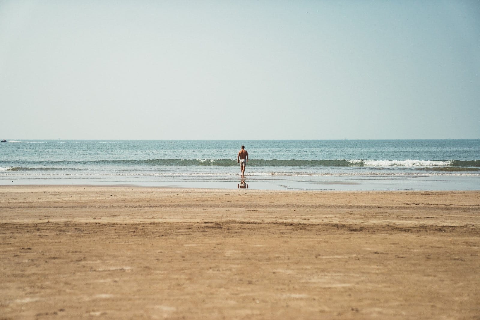 A lone figure at the water’s edge on a wide Goan beach