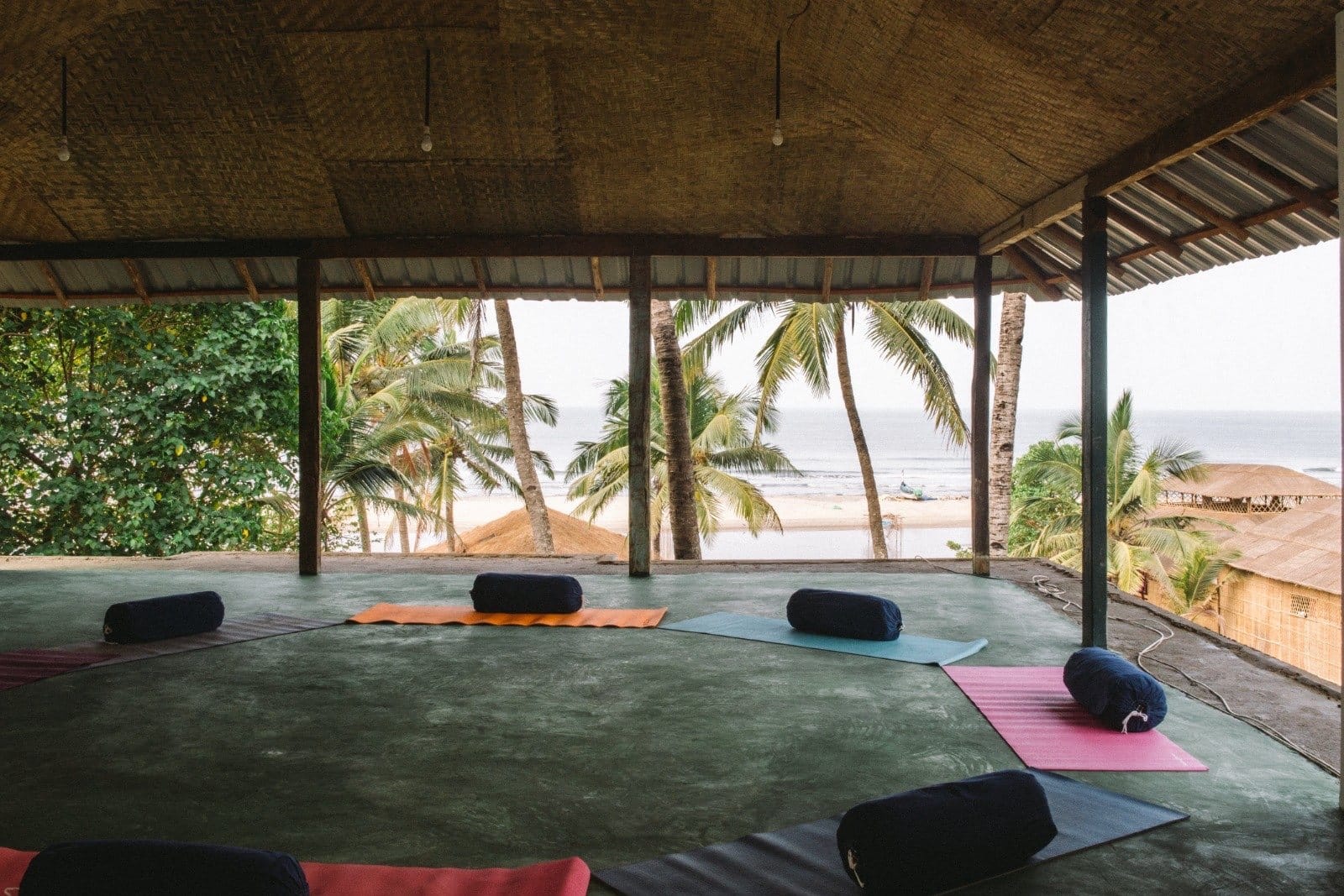 An open-sided yoga shala looking out to palms and the sea
