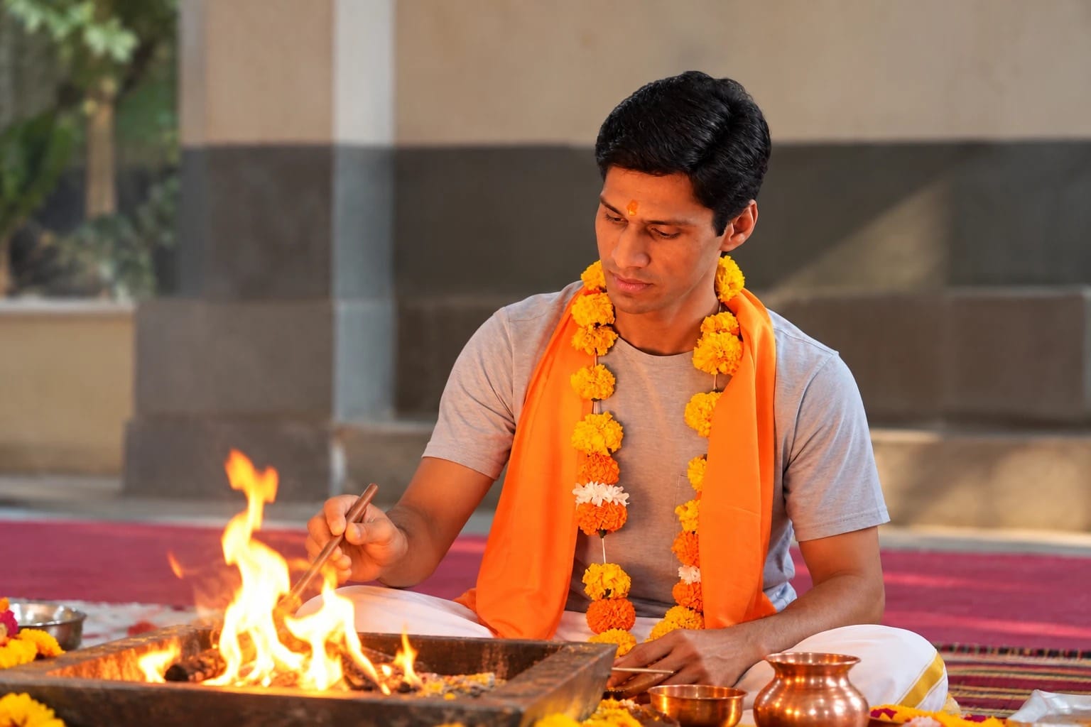Yogi Madhav offering to a havan fire, wearing a marigold garland, in India