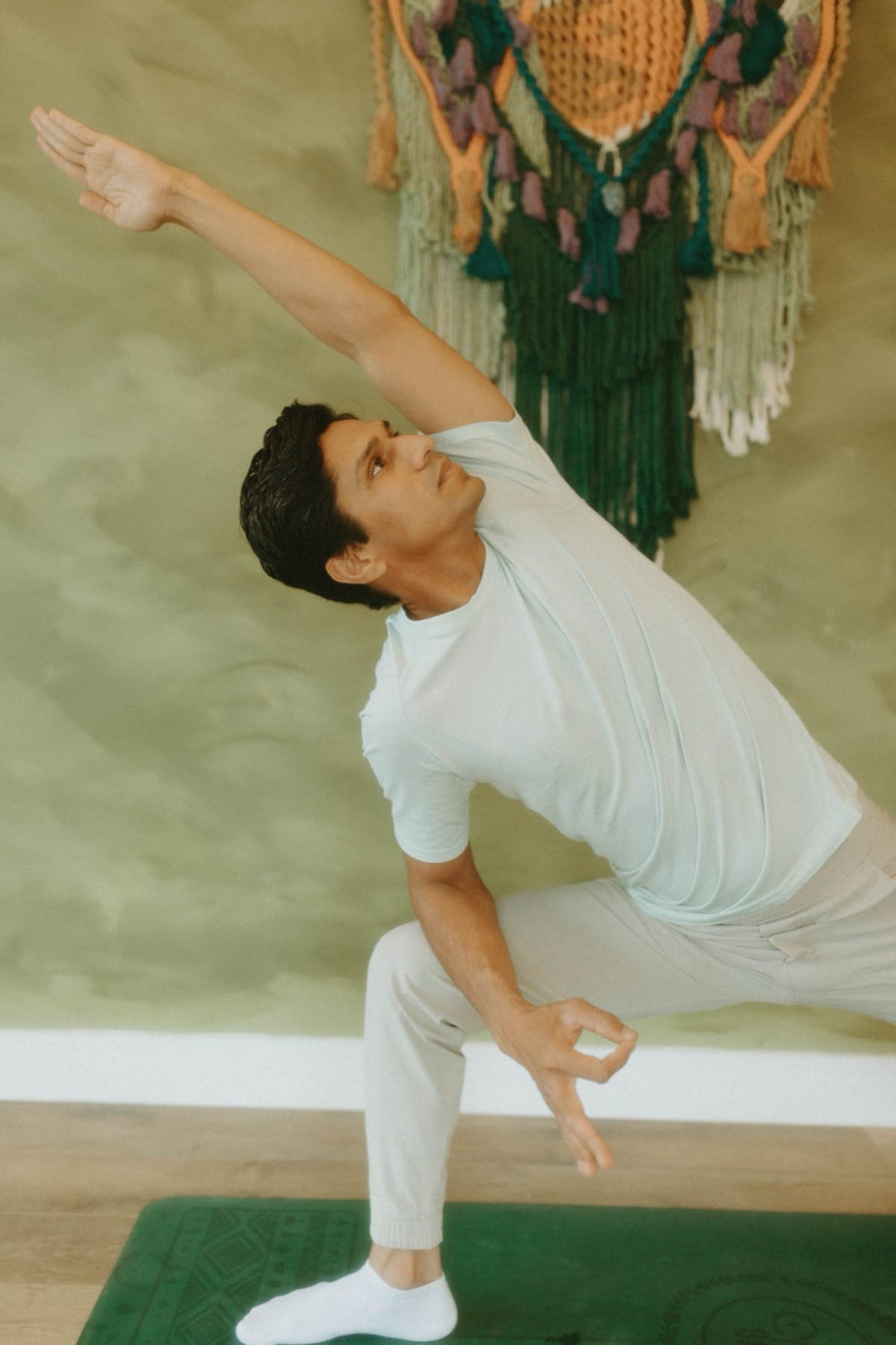 Yogi Madhav reaching one arm overhead in a studio in North Wales