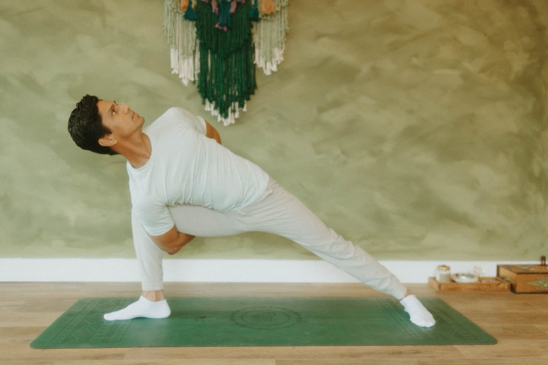 Yogi Madhav in a side angle pose in a studio with a sage green wall in North Wales